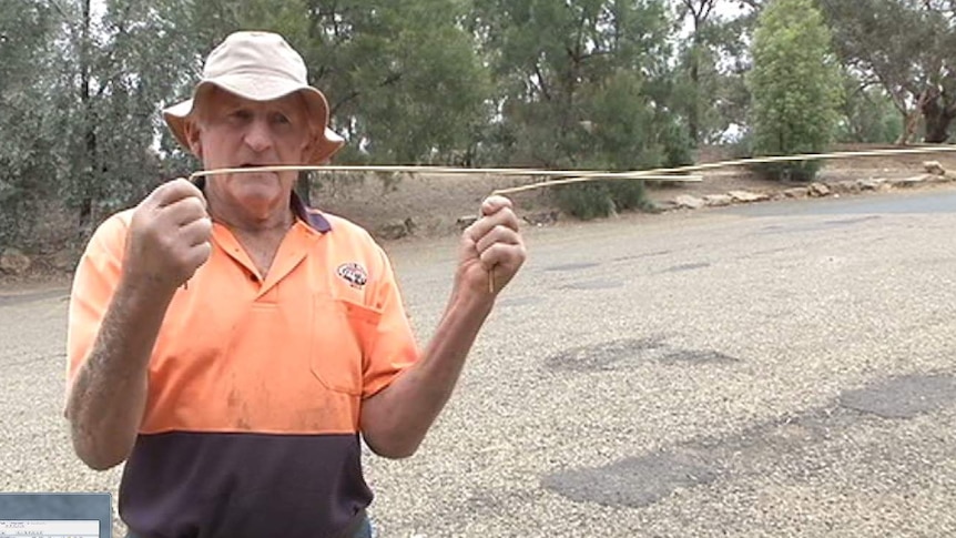 Man holding two brass rods in front of him