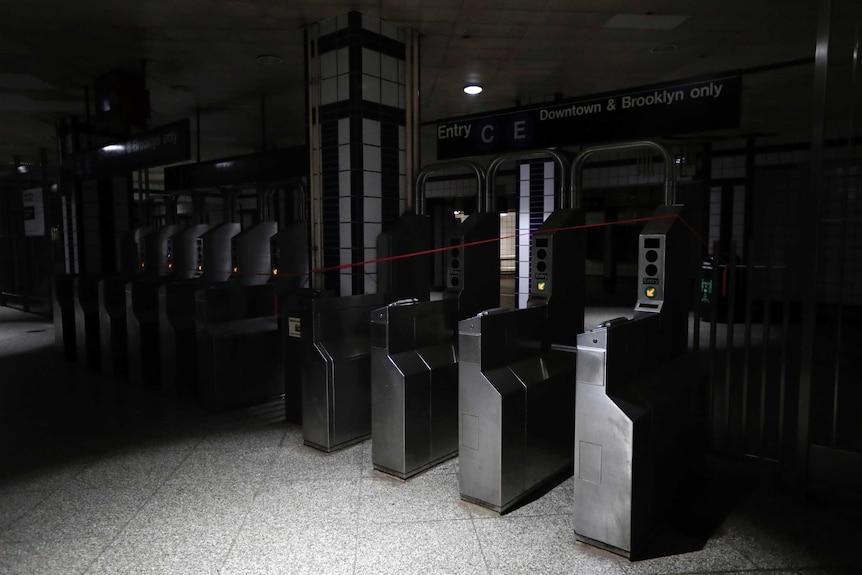 Entry barriers to the subway are shrouded in darkness.
