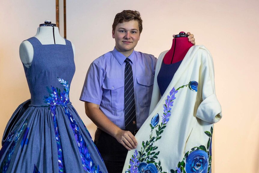 Connor O'Grady, dressed in his school uniform, shows off some of the dresses he has designed.