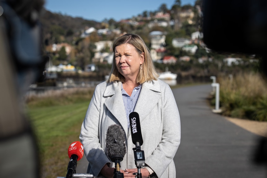 Bridget Archer se tient devant un micro lors d'une conférence de presse.