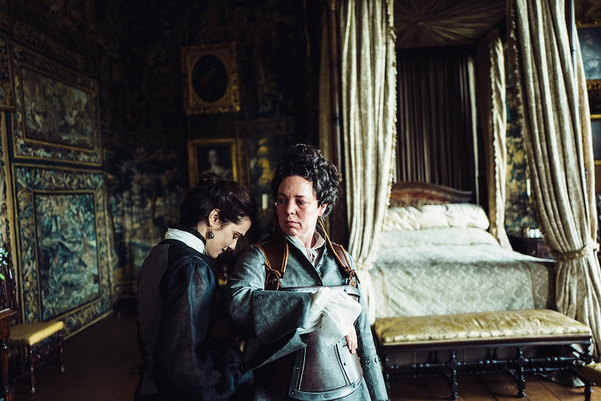 Colour still of Rachel Weisz and Olivia Colman having an intimate moment in 2018 film The Favourite.
