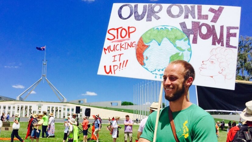 A protestor holds a sign reading 'Our only home — stop mucking it up!!!' outside Parliament house in Canberra, during protests.