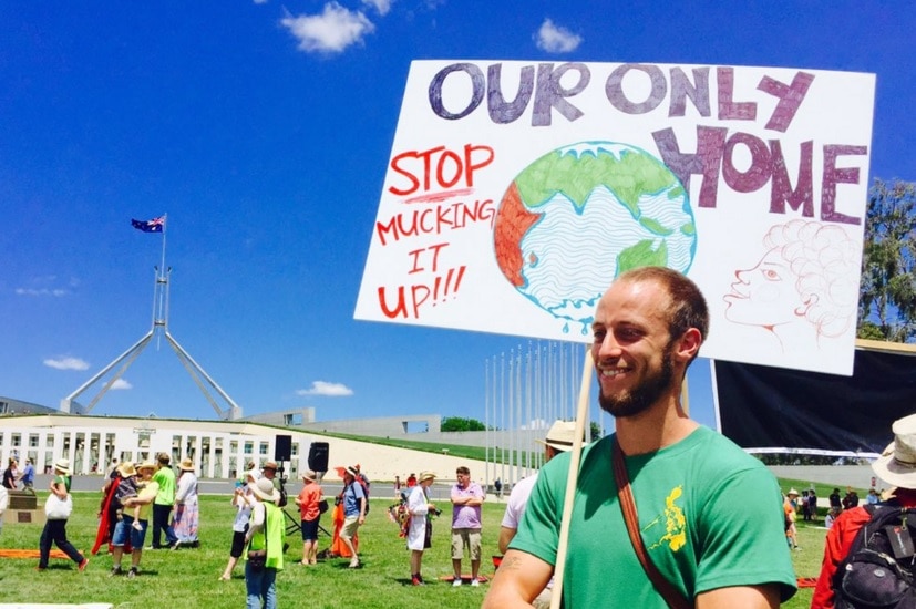 A protestor holds a sign reading 'Our only home — stop mucking it up!!!' outside Parliament house in Canberra, during protests.