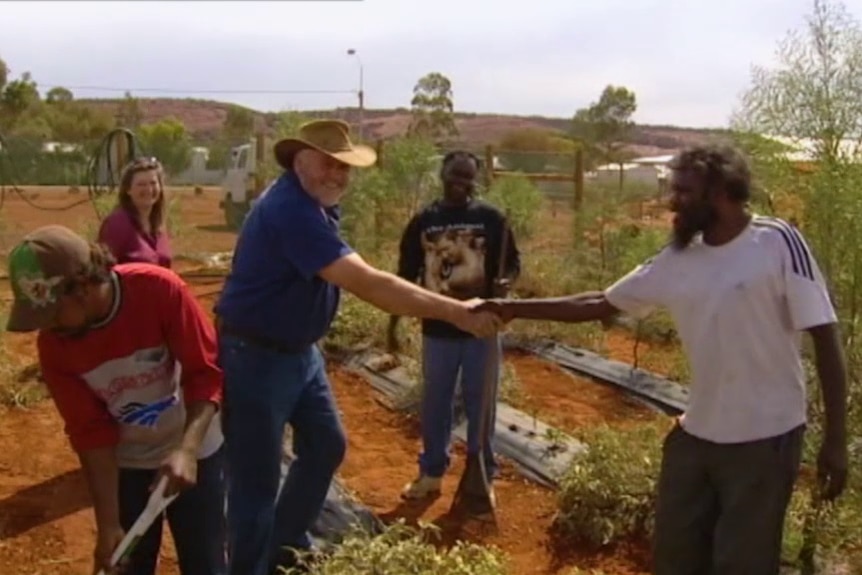 Two people shake hands in a community garden