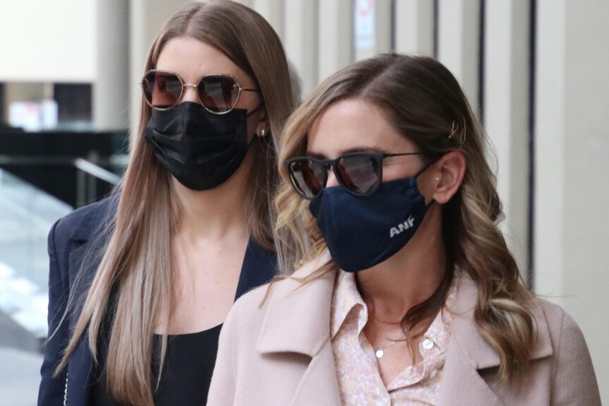 A head and shoulders shot of two women wearing black masks and sunglasses leaving the Perth Coroner's Court.