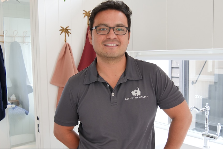 Fabio Paulucci wearing collared shirt with Aussie Tiny Houses logo inside white tiny house kitchen