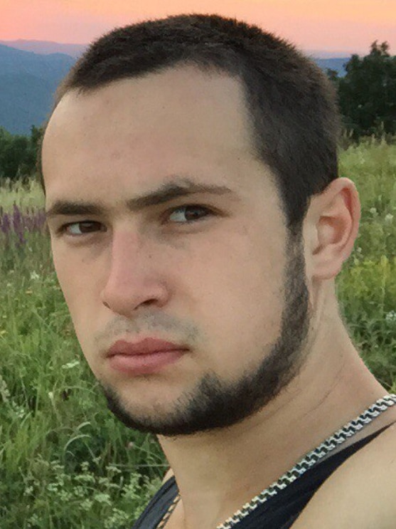 A dark haired young man in a field 