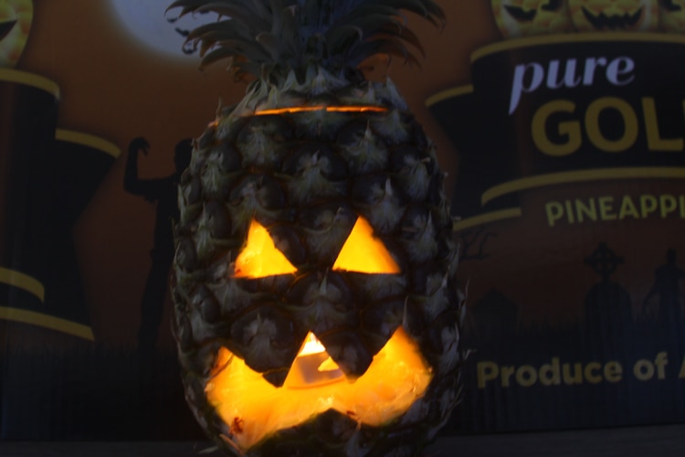 a pineapple that's been carved out with a scary face, with a candle inside lighting up the face.