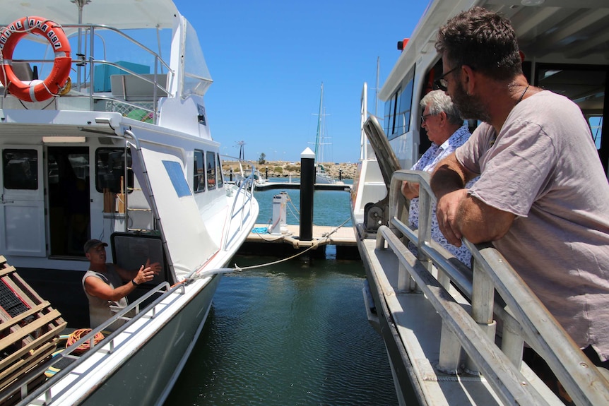 Lobster fishermen stand on their boats chatting about the Government's proposed changes to the industry.