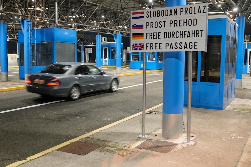 A car is driven through a former border checkpoint pass a sign saying "free passage" in Croatian, Slovenian, German and English.
