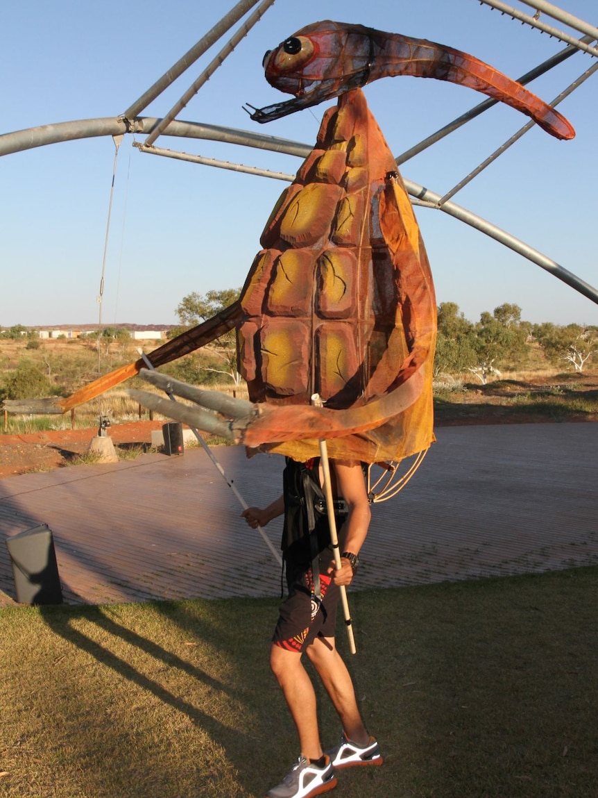 A person with a giant puppet resembling a fantasy creature.