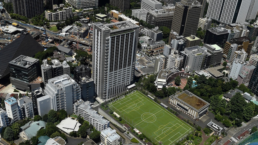 An aerial shot of Tokyo with a large soccer field in the middle. 