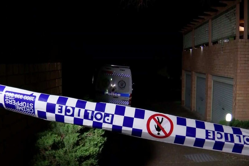 Police tape in front of a red brick unit block.