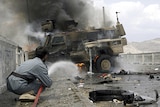 An Afghan policeman tries to put out fire from a burning US armoured vehicle.