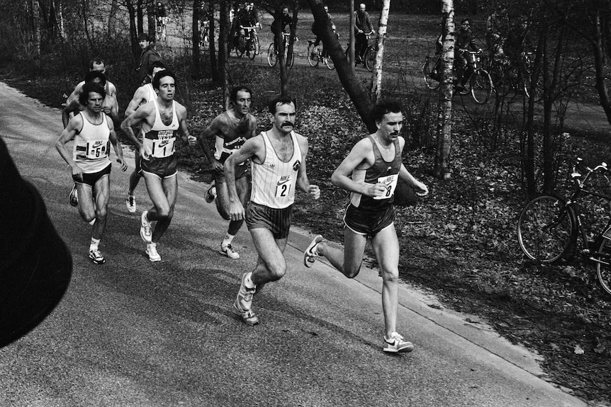 Rob de Castella runs near the front of the pack through a park in rotterdam.