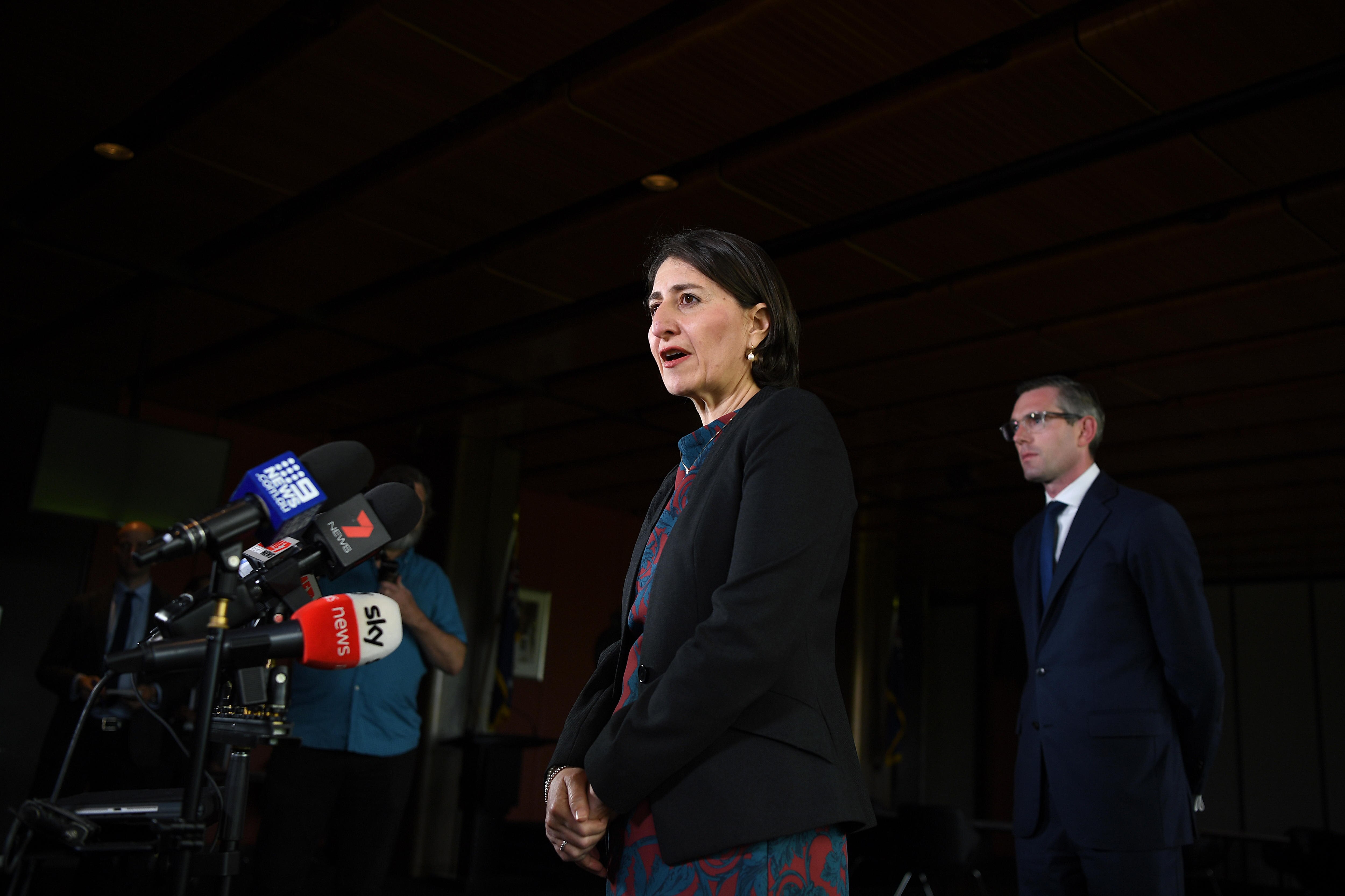 Gladys Berejiklian speaks into microphines while Dominic Perrottet stands behind her.