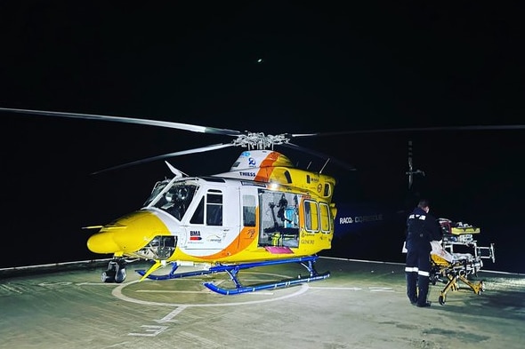 A helicopter on a helipad with a stretcher nearby