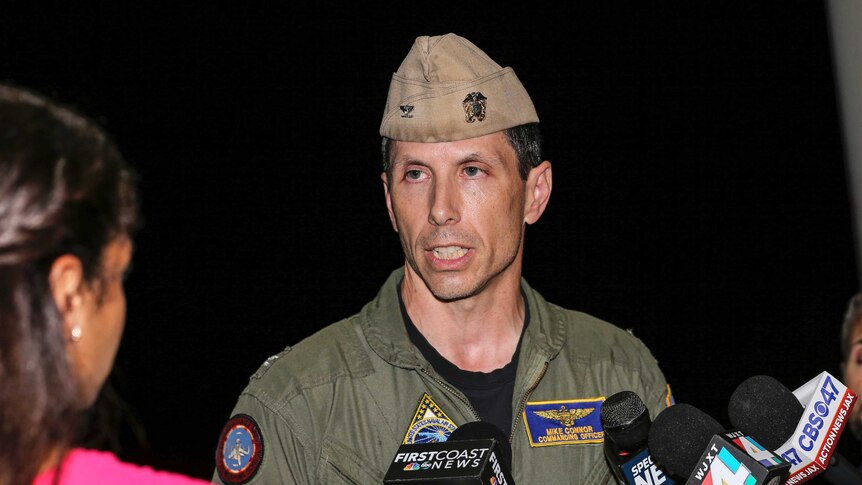 A man wearing a military uniform talks to news reporters.