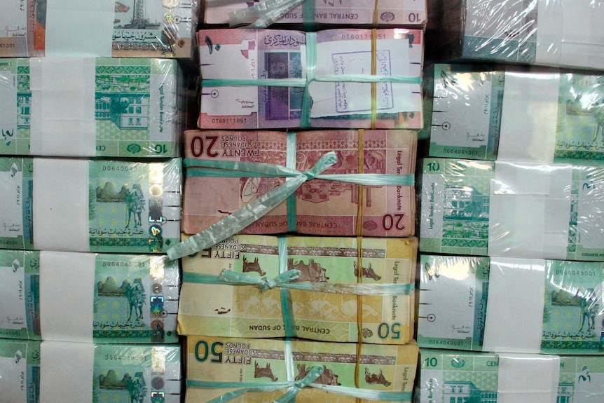 Stacks of Sudan's banknotes displayed behind a window at a bank.