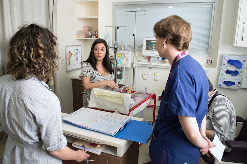 Rachel talks with medical staff as they do their rounds of the neonatal intensive care unit.