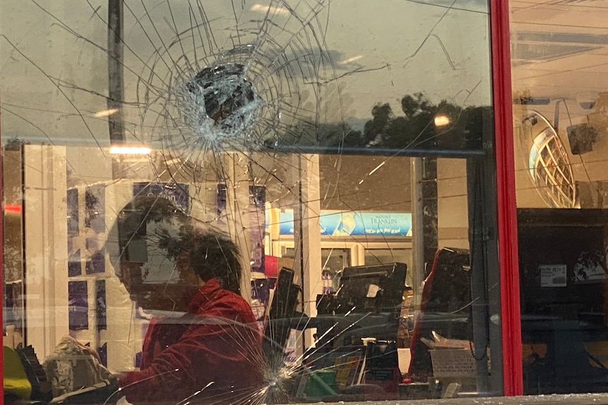 Snashed window with woman inside wearing red t-shirt.