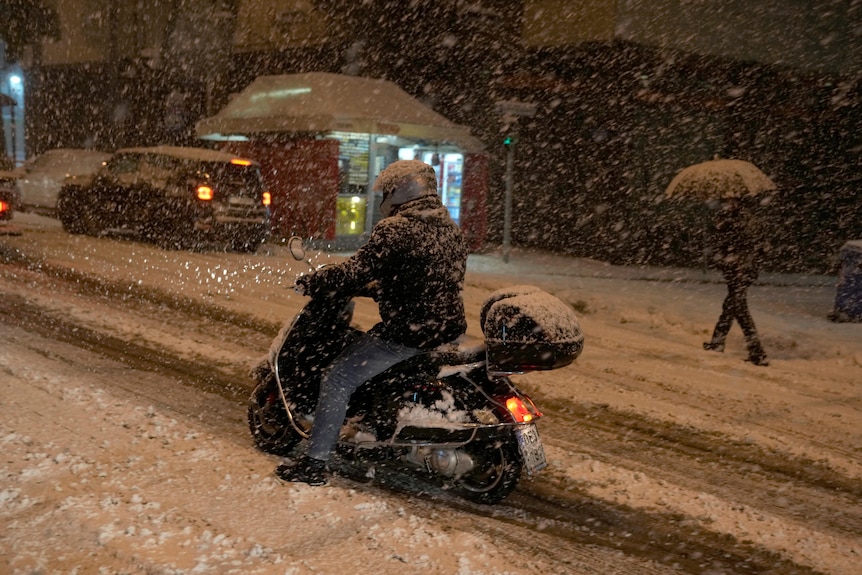 A man tries to ride on a snow-covered road during a snowstorm in Athens