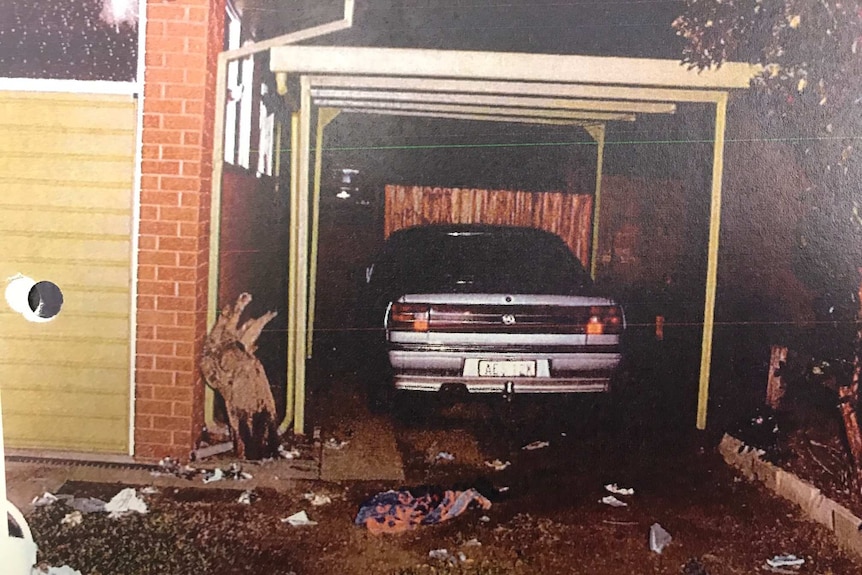 Car port with car in it and signs of an explosion.