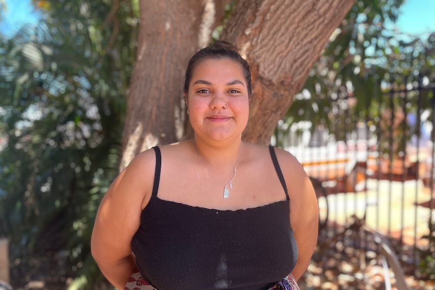 Woman smiles in front of mango tree 