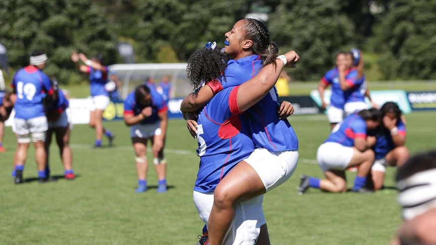 Two female rugby players celebrate.