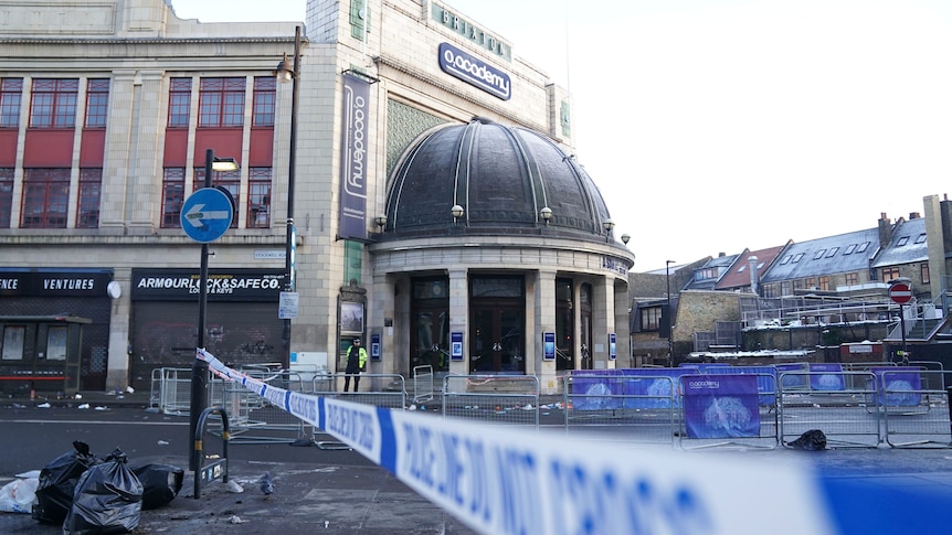 blue and white poliec tape and fencing is seen in the road outside the Brixton Academy concert venue in London at daytime