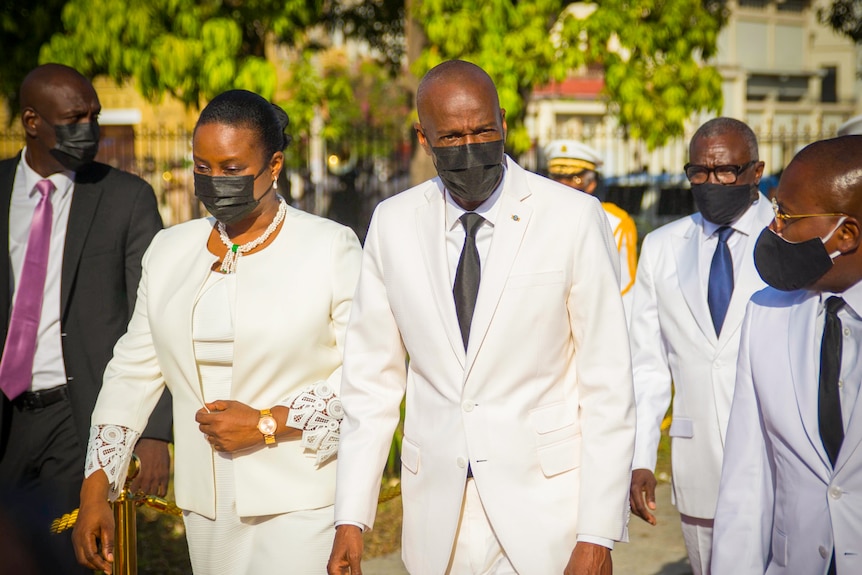 Jovenel Moise and Martine Moise in all-white outfits and black face masks 