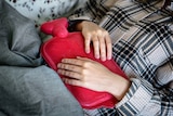 close up of woman holding hot water bottle on her stomach