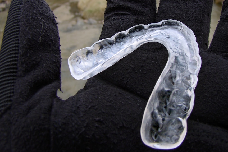 A clear mouthguard in a person's hand