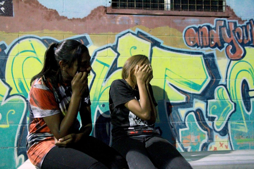 girls cover their faces with hands while sitting on silver seat