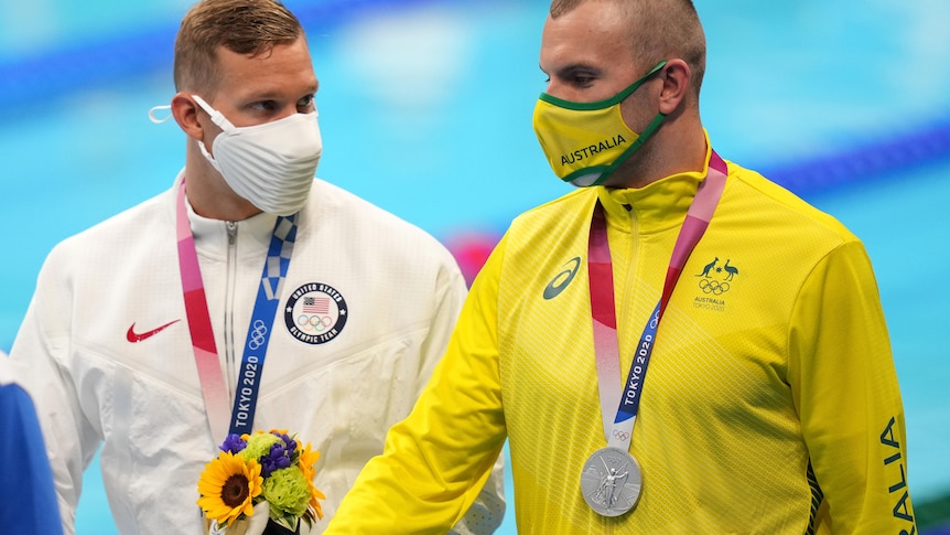 Man wearing white sweater with medal, man wearing yellow sweater with medal