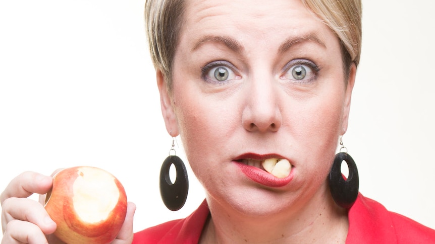 Woman pictured taking a bite out of an apple.