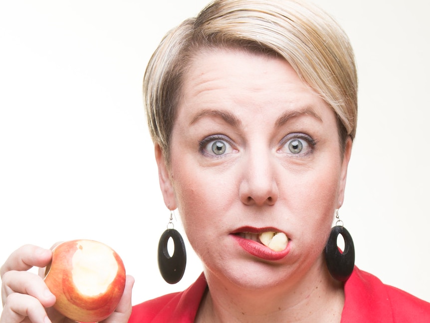 Woman pictured taking a bite out of an apple.