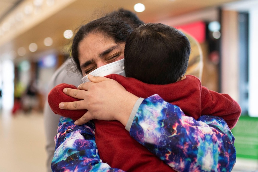 An emotional woman hugs a toddler to her tightly