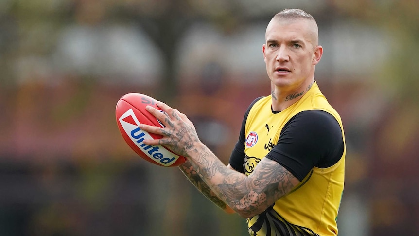 An AFL player holds the ball in front of him as he looks downfield after taking a mark at training.