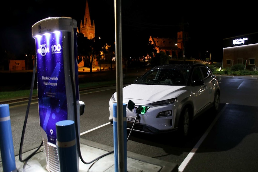 Electric car charging with charging bowser in the foreground.