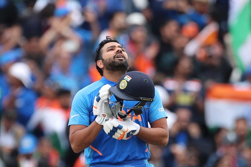 A cricketer holds his helmet as he looks to the sky after making a century.