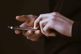 A man's hands, holding and using an iPhone.