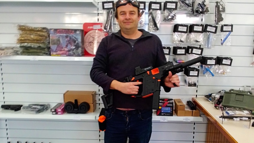 Man holds a gel blaster in a shop