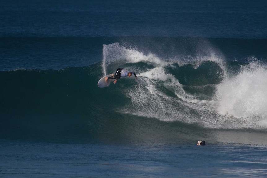 Man carving up a wave on his surf board.