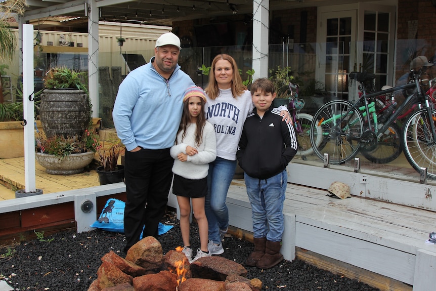 A family of four stand in front of a fire in their backyard. A man and woman, and two children aged 9 and 11