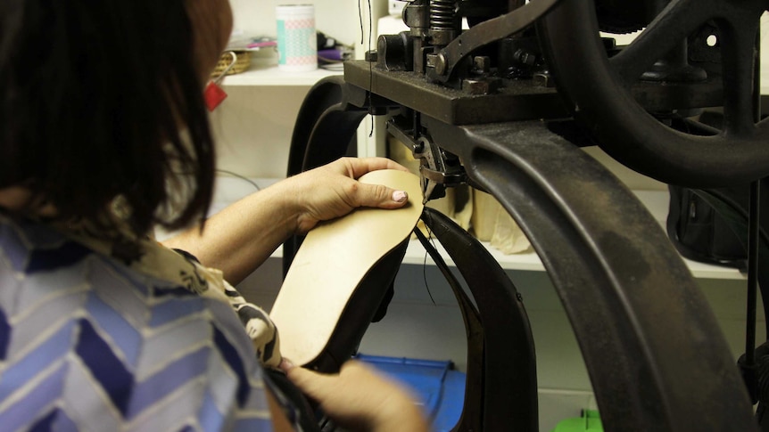 a woman sews leather on an old machine