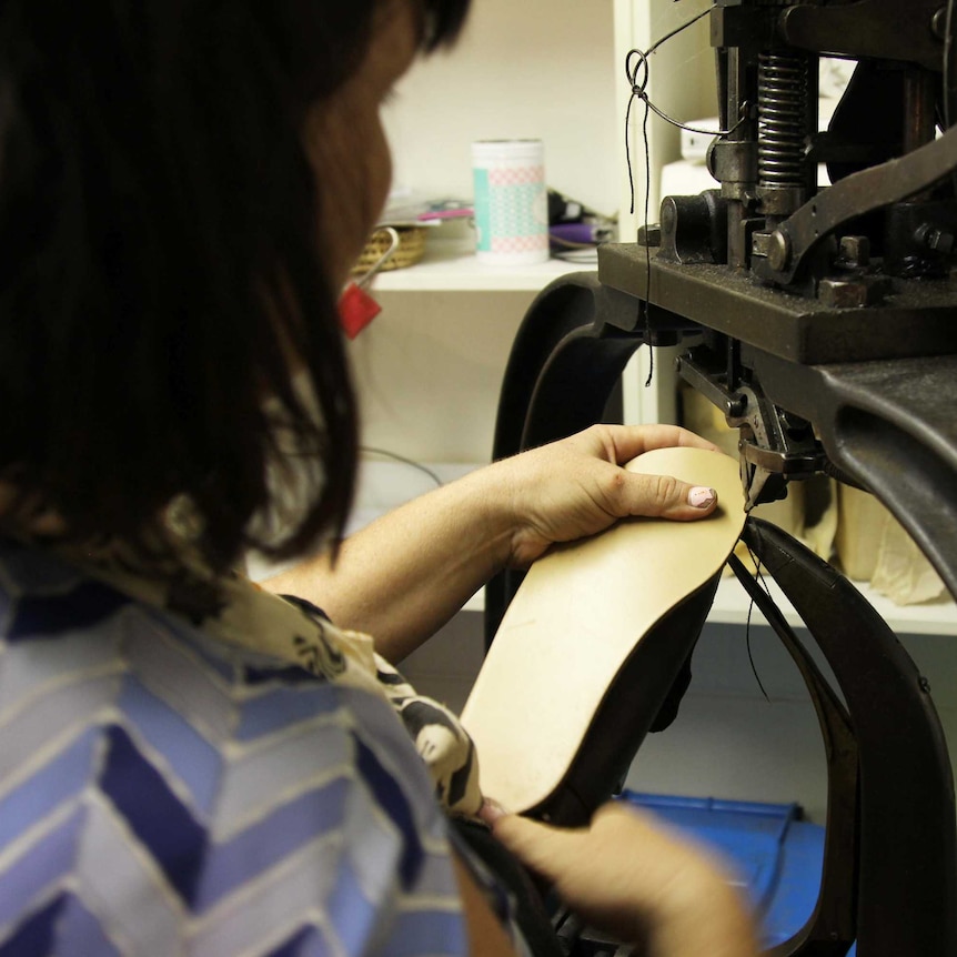 a woman sews leather on an old machine