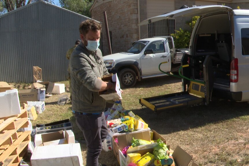 A man packing boxes of groceries together, ready to be placed into the back of a van in Wilcannia. 