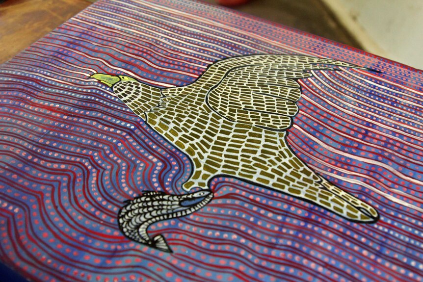 A dot-painting style artwork depicting an eagle flying with a barramundi.