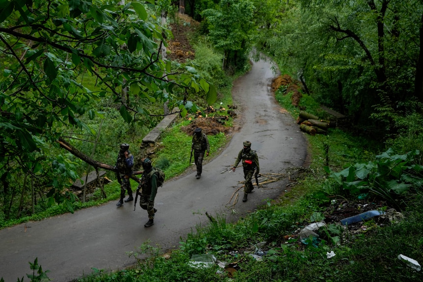 四名士兵沿着一条狭窄蜿蜒的小路穿过绿地。